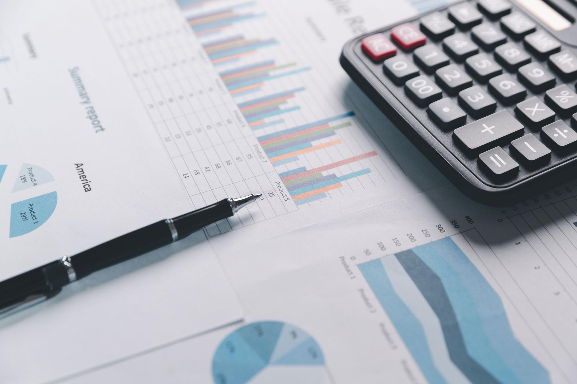 Auditor reviews financial statement and balance sheet on desk using a calculator, representing the concept of accounting, audit, and finance in preparing a detailed financial report for the business.