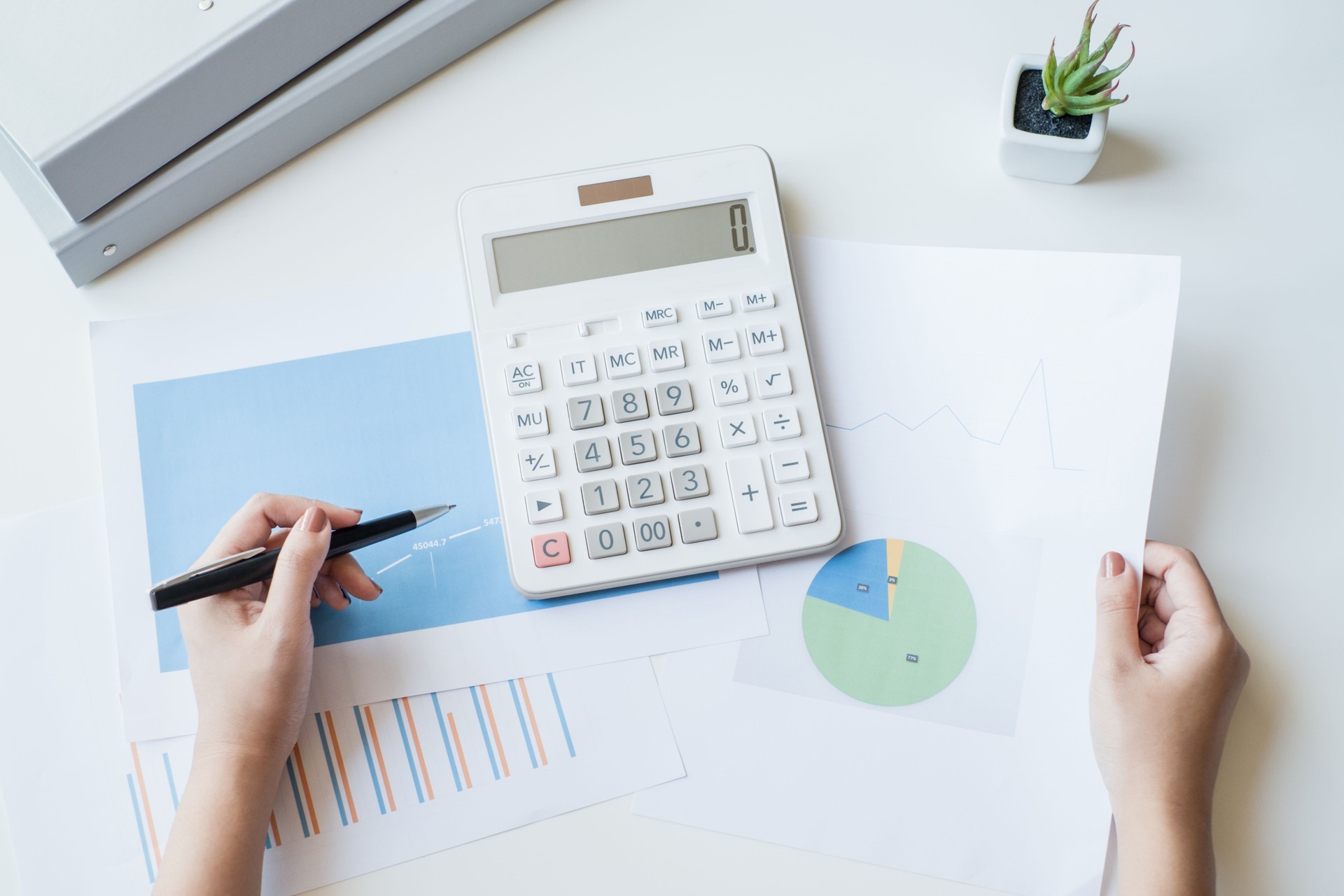 Businesswoman using a white calculator to calculate the value of business financial